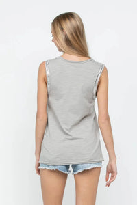 Woman wearing a gray sleeveless top and denim shorts on a white background